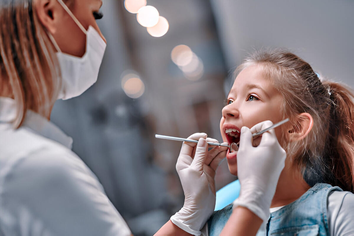 Smiling child sitting in a dental chair with a friendly pediatric dentist